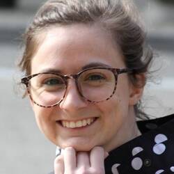Rose White wears large-framed glasses and a polka dot shirt.